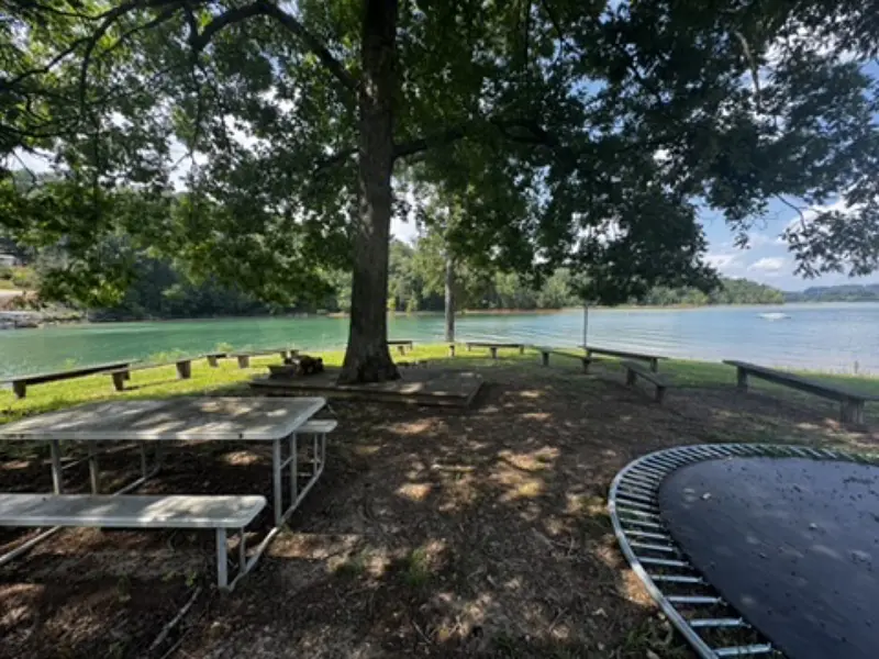 Lakeside picnic tables in the shade at camp